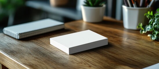 Fototapeta premium A white notepad on a wooden desk with other office supplies.