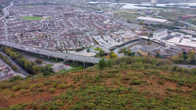 Sideways Aerial View of Port Talbot Town with M4 Motorway with Steady Traffic with Cars, Vans, Lorries. Rows of Houses and Local Theatre Building 4K.