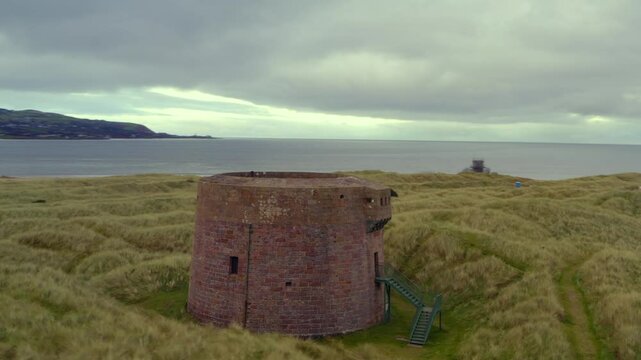 Aerial orbit of the Magilligan Martello Tower, revealing Lough Foyle and the Donegal coastline in the distance