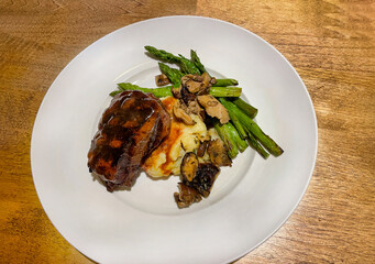 Grilled filet mignon served with mashed potatoes and asparagus and topped with gravy and sautéed mushrooms.