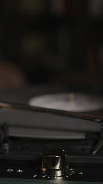 Vintage turntable close-up. Needle glides across the spinning silver record. One hand operates the pickup. 4k vertical video.