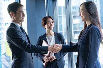 会議室で握手をするスーツを着た男女