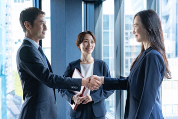 会議室で握手をするスーツを着た男女