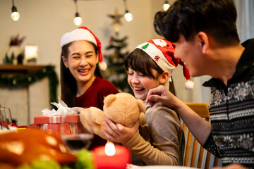 Asian family giving gift box to young daughter during Christmas party.