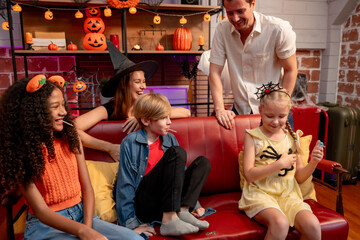 Multiracial family celebrating Halloween party together in house. 