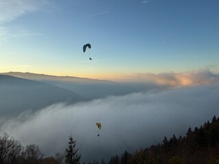 Parapente au dessus du Lac d' Annecy. Vol de parapente en montagne au dessus du brouillard. Sport extrême. Voler le soir au dessus de la brume avec un coucher de soleil.