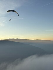 Parapente au dessus du Lac d' Annecy. Vol de parapente en montagne au dessus du brouillard. Sport extrême. Voler le soir au dessus de la brume avec un coucher de soleil.