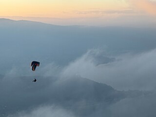 Parapente au dessus du Lac d' Annecy. Vol de parapente en montagne au dessus du brouillard. Sport extrême. Voler le soir au dessus de la brume avec un coucher de soleil.