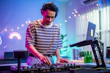 Asian young man artist DJ mixing and scratching music mixer controller. 