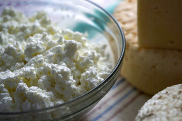 Cup of cottage cheese. An assorted collection of Artisan Cheeses beautifully arranged on a vibrant Striped Cloth