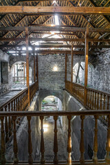 Interior of an old abandoned winery. Stone walls, wooden railings and stairs and windows, destroyed roof, long corridors, basements