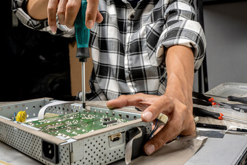 Man technician repairing television with a screwdriver