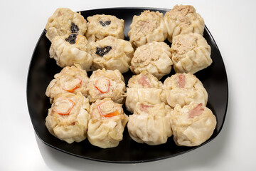 Assorted chinese dim sum dumpling on the plate isolated over white background