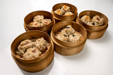Assorted chinese dim sum dumpling on bamboo wooden basket bowl isolated over white background
