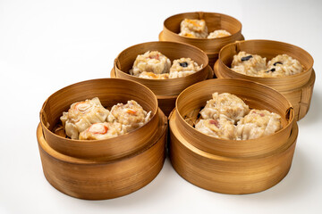 Assorted chinese dim sum dumpling on bamboo wooden basket bowl isolated over white background