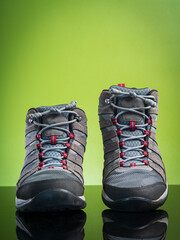 Vertical image, studio shoot a pair of black gray hiking boots, shoes isolated on natural green background