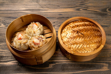 Chinese dim sum dumpling on bamboo wooden basket bowl on wooden table