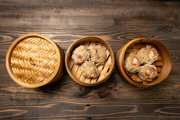 Assorted chinese dim sum dumpling on bamboo wooden basket bowl on wooden table