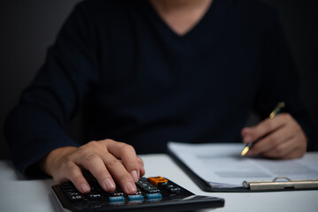 Businessperson calculating financial figures with a calculator, representing financial planning,...