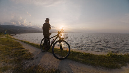 Fototapeta premium Silhouette of a cyclist on the shore of the lake.