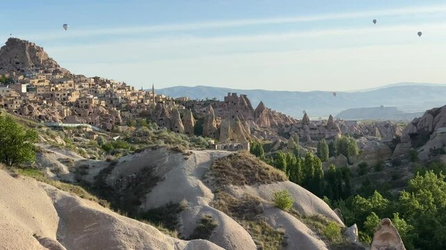 Hot-air balloons flying over Uchisar town (belde) on a sunny day in Nevsehir, Cappadocia, Turkey