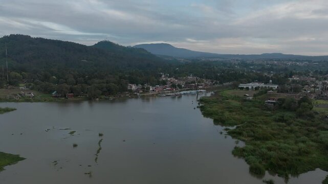 DRONE: REVEAL SHOT OF PATZCUARO LAKE HARBOR AT SUNSET ON A CLOUDY DAY