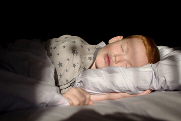 boy sleep in the bed. the child lies on pillow under blanket. 