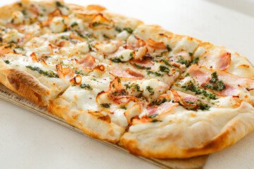 Pizza with bacon in Roman style served with fresh tomatoes on white table at cozy home