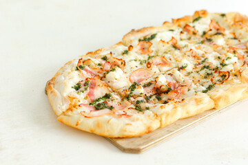 Pizza with bacon in Roman style served with fresh tomatoes on white table at cozy home