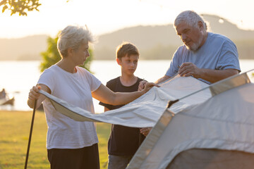 Family Setting Up a Tent Together Outdoors, Highlighting Camping, Bonding, and Generational Connection, Capturing the Joy of Spending Time in Nature, Teamwork, and Outdoor Adventure at Sunset.