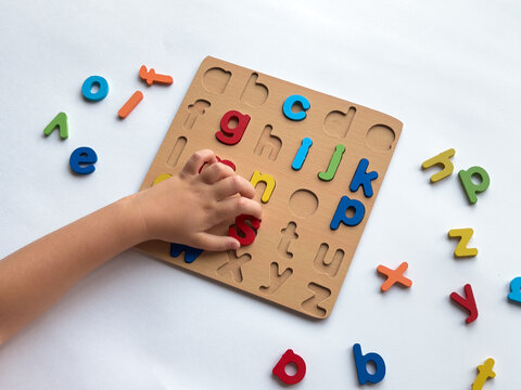 Child learning alphabet with colorful wooden puzzle for early education