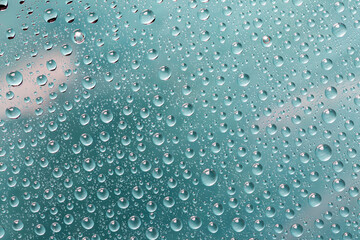 Water drops on light green glass lighted trought by lamp