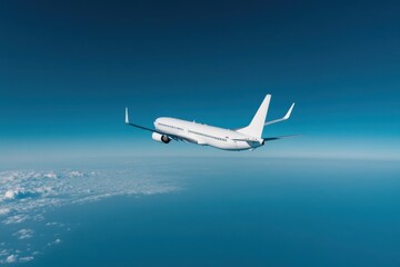Fototapeta premium White passenger airplane flying above the clouds in the blue sky