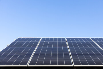 Aerial view of solar panel cells on clear blue sky background. Alternative energy concept. Modern house with solar panels stand-alone photovoltaic plant system on household metal sheet roof