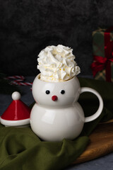 Christmas snowman mug with hot chocolate, whipped cream and marshmallows. Christmas Eve in a cozy home with a hot cocoa drink