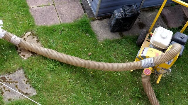Old insulation suction machine, vacuum, large sack and hose; old loose fill insulation mineral wool moving inside the hose; overhead, top view.
