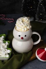 Christmas snowman mug with hot chocolate, whipped cream and marshmallows. Christmas Eve in a cozy home with a hot cocoa drink