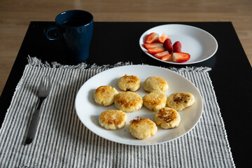 A plate of cheesecakes with strawberries and coffee for breakfast 