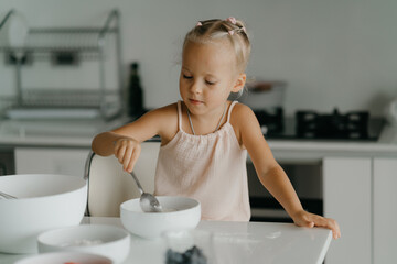 Cute little girl making a cake in kitchen