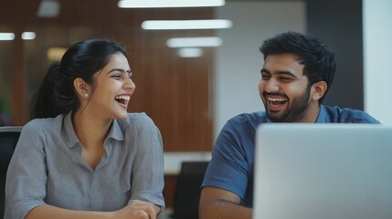 Laughing young Indian executives corporate workers teammates of diverse gender use computer app together enjoy conversation discuss funny work situation. Two colleagues friends having fun on workplace