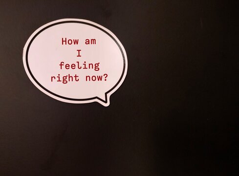 Paper sticker with question HOW AM I FEELING RIGHT NOW? concept of checking in with yourself - key step toward understanding your mental and emotional state to attune to your own needs and feelings