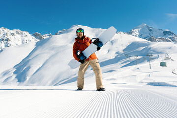Happy snowboarder have fun holding snowboard standing and posing along ski slope at  resort prepared by snowcat