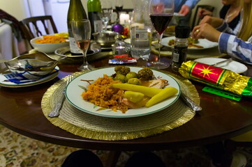 A plate of Christmas dinner with defocused hands of people eating in the background