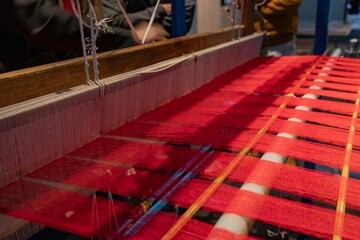 Traditional loom weaving red fabric close-up