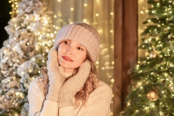 Woman Christmas Lights Winter - Young woman wearing a hat and gloves smiling in front of Christmas lights and trees.