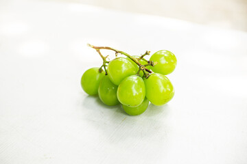 A sprig of sweet green grapes on a white table
