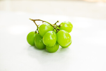 A sprig of sweet green grapes on a white table
