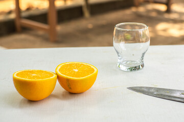 Oranges that are cut and the juice will be squeezed into a clear glass