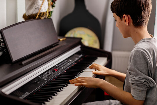 Side view of boy playing digital piano at home