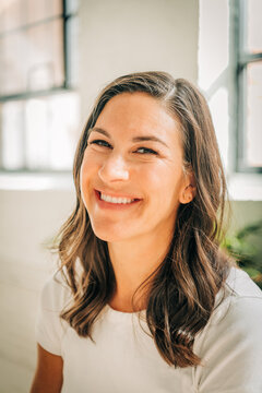 Close-up of a smiling woman with wavy hair and natural lighting